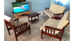 A living room with a wooden sofa set, a coffee table, and a television on a wooden stand.