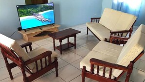 Uma sala de estar com televisão, móveis de madeira e piso de azulejos.