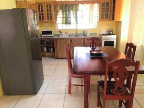 Enjoy meals in this cozy kitchen with a dining table and chairs, featuring a refrigerator, microwave, and stove.