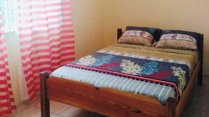 A single bed with a wooden frame in a room with a tiled floor and a plain wall. - Very clean 2-bedroom Apt. in St. Georges, Grenada (Saint George's)