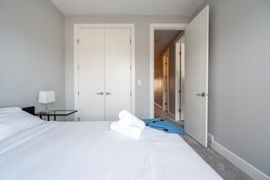 A hotel room with a bed, a nightstand, a lamp, and a blue towel. - Downtown views across from Stampede Park!  (Calgary)