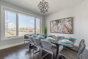 A dining area with a large table set for six, large windows, and a city view. - Downtown views across from Stampede Park!  (Calgary)
