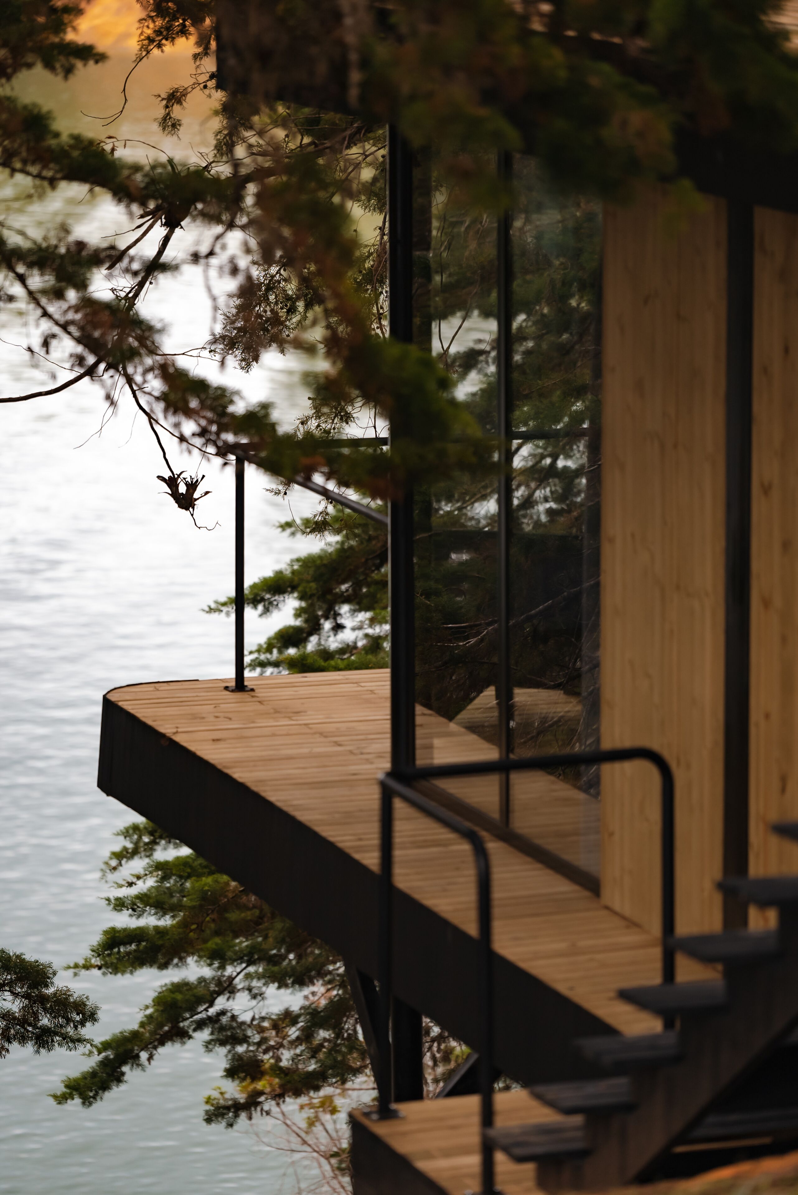 A wooden deck with a staircase leading to a building, overlooking a body of water.