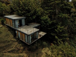 Una baita moderna con facciata in legno, ampie finestre e un balcone.