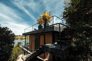 Una casa moderna con facciata in legno, una scala e vista su un lago.