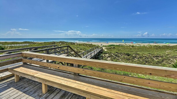 A wooden boardwalk leading to a beach with a clear view of the ocean and distant shoreline. - Emerald Isle Vacation Rental w/ Resort Pool! (Emerald Isle)