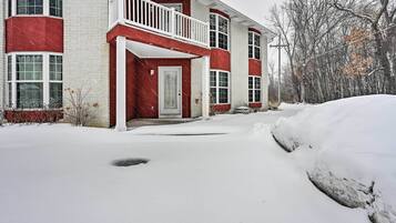A two-story building with a red and white exterior, a balcony, and a snow-covered driveway.