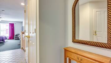 A room with a wooden console table, a large mirror with a decorative frame, and a door leading to another room.