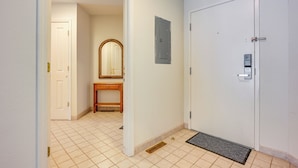 Un pasillo con una puerta blanca, un banco de madera y un espejo en la pared.