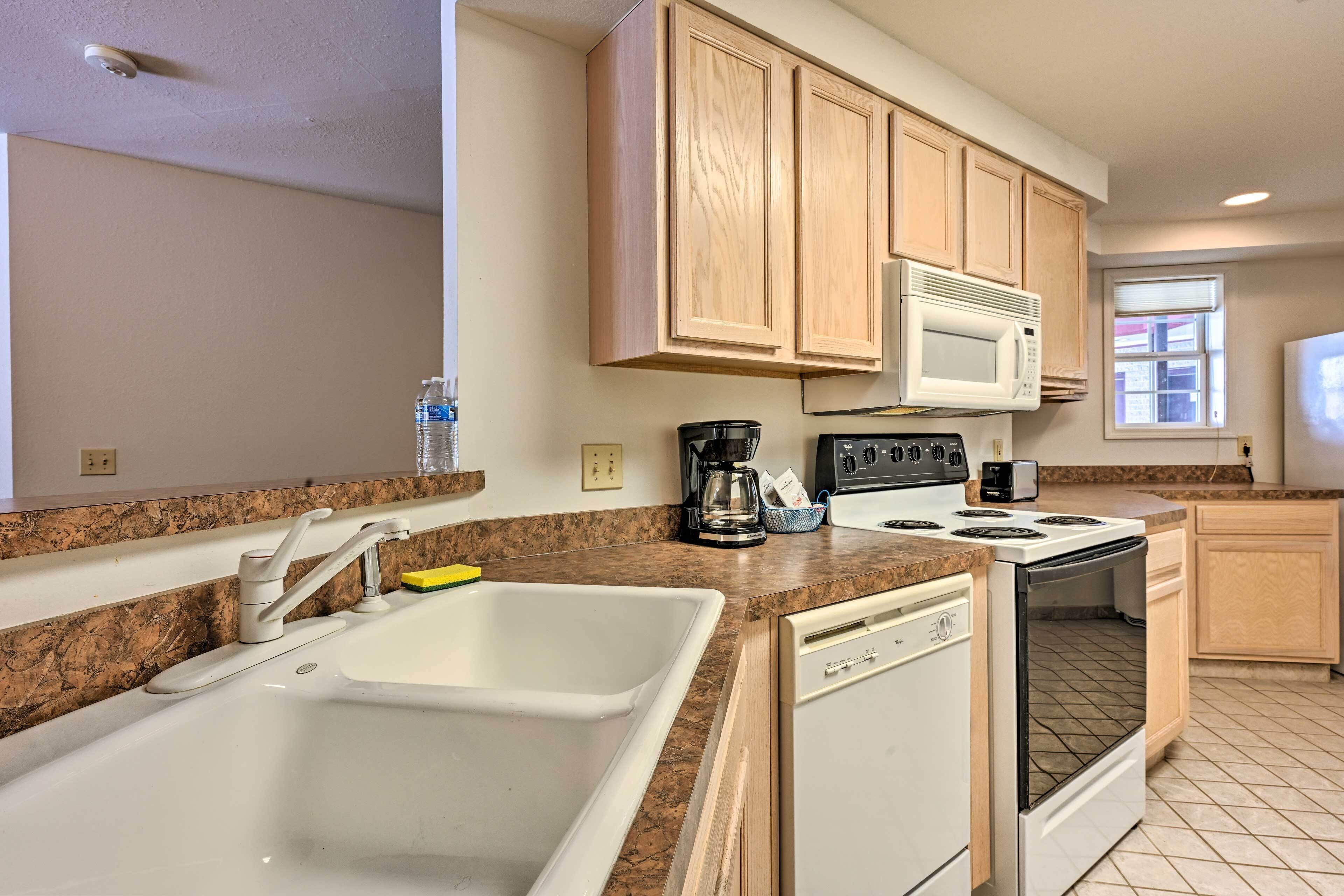 A kitchen with a double sink, a stove, a microwave, and wooden cabinets.