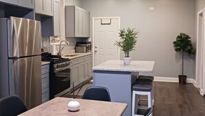 Una cocina moderna con horno empotrado, refrigerador de acero inoxidable y comedor con mesa y sillas.