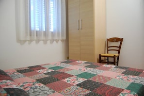 Una camera da letto con un letto, un armadio in legno, una sedia e una finestra con tende.