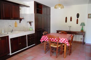 Una cucina con mobili in legno, un lavandino bianco e un tavolo da pranzo con tovaglia a pois rossi.