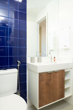 A bathroom with a white sink, a mirror, and a blue tiled wall.