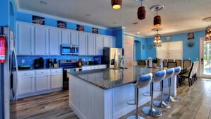 Una cocina con armarios blancos, encimera de granito y una isla central con taburetes de bar.