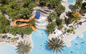 An aerial view of a resort with multiple swimming pools, a water slide, and lounge areas surrounded by palm trees. - Floridian Cabana by All Vacation Dreams (Davenport)