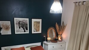 En pænt redt seng med to puder, et natbord med en lampe og billedkunst på væggen.