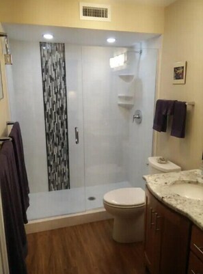 A bathroom with a shower enclosure, toilet, and vanity.