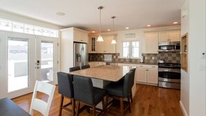 Una cocina moderna con una isla central, electrodomésticos de acero inoxidable e iluminación colgante.