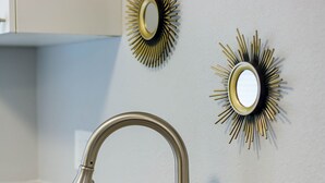 A bathroom with a modern faucet and two sunburst mirrors on the wall. - Sleeps 4 Hot Tub Fenced INN  (Tampa)