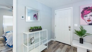 A hallway with a white console table, a door, and a wall with a framed artwork. - Sleeps 4 Hot Tub Fenced INN  (Tampa)