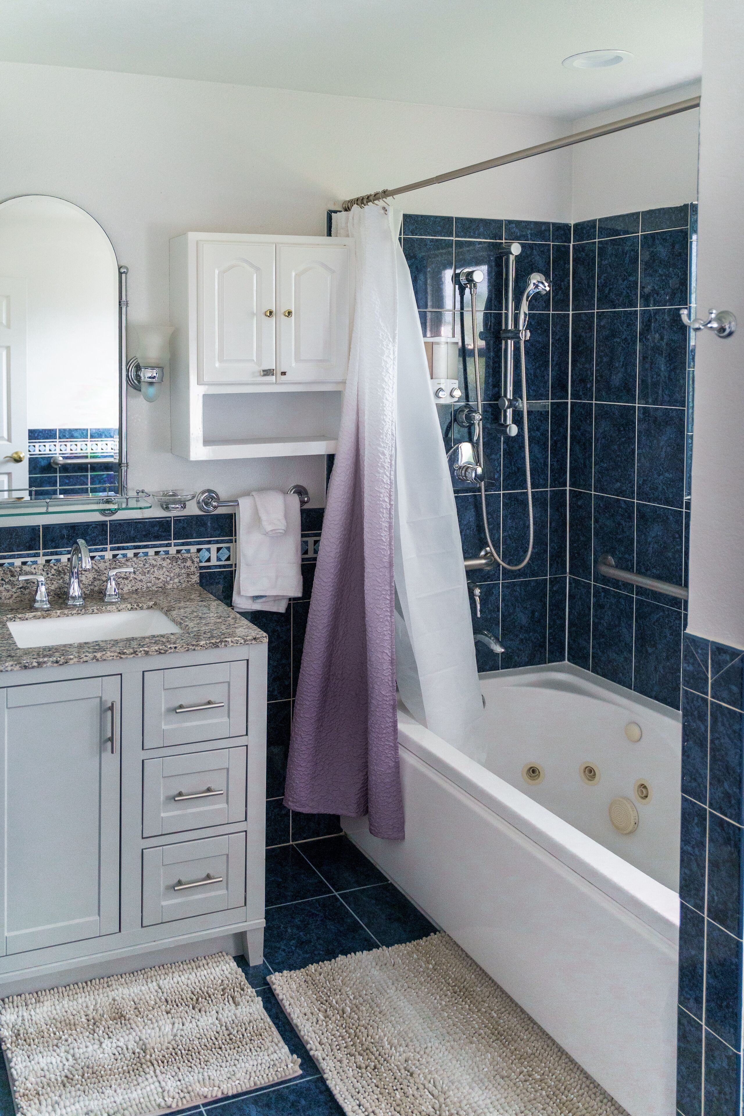 A bathroom with a bathtub, shower, and vanity with a mirror.