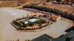 An aerial view of a property with a swimming pool, outdoor seating, and a stone wall. - Finca El Mirador (Valle de Guadalupe)