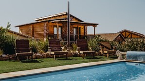 A pool area with a wooden house, lounge chairs, and a stone pathway. - Finca El Mirador (Valle de Guadalupe)