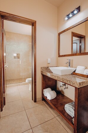 Un baño con un espejo grande, un lavamanos y una zona de ducha.