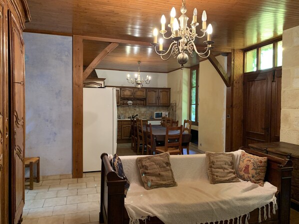 Cozy space with a traditional dining table for four, comfortable sofa, and ornate chandelier.