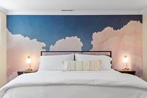 A bedroom with a bed, white bedding, two bedside tables with lamps, and a large abstract mural on the wall. - Chattanooga Suite | 5 Min Downtown | Tempurpedic | Standing Desk | 205 Mbps WiFi (Chattanooga)