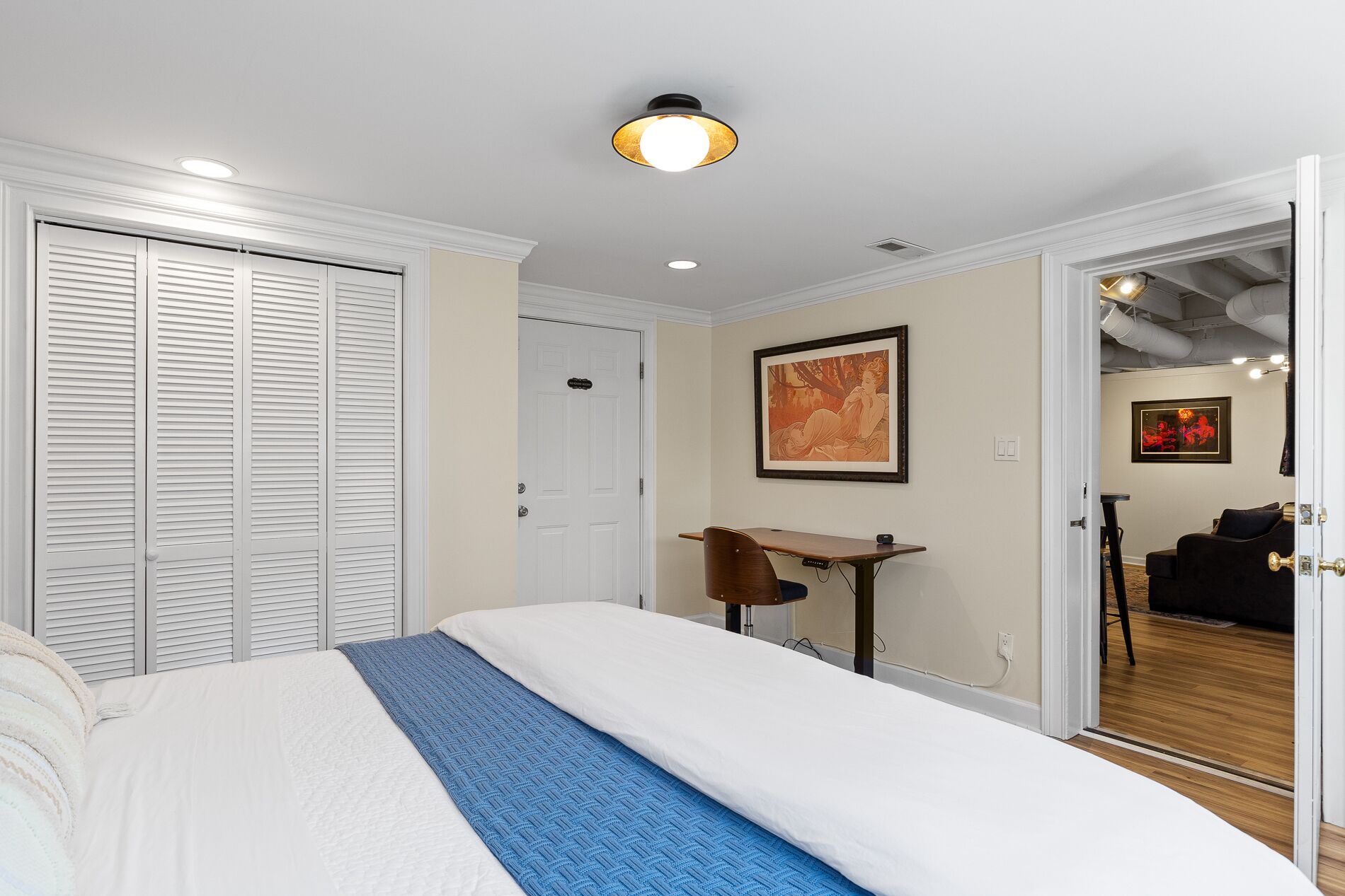 Habitación de hotel con cama, escritorio y silla. Se ve una puerta que da a otra habitación.