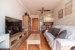 A modern living room with a flat-screen TV, wooden entertainment unit, and a sofa with cushions.