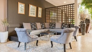 Una sala de estar moderna con un sofá seccional, dos sillones, una mesa de centro y un separador decorativo.