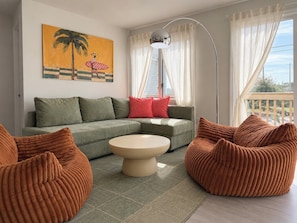 A living room with a sofa, ottoman, and a painting on the wall.