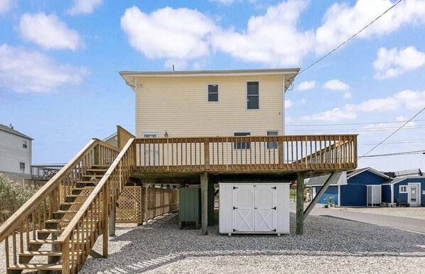 Une maison à deux étages avec une terrasse en bois et un garage.