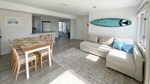 Un vaste espace de vie comprenant une table à manger, un canapé et une décoration sur le thème du surf.