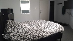 A bedroom with a bed, a wardrobe, a mirror, and a television.