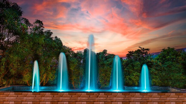 A fountain with multiple jets of water against a backdrop of trees and a sunset sky. - Chinar Wood Resort Dapoli (Dapoli)