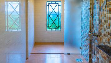 A modern bathroom with a toilet, a shower, and a window with a geometric design.