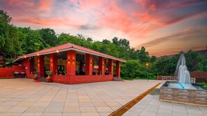 A red building with a tiled courtyard and a fountain. - Chinar Wood Resort Dapoli (Dapoli)