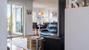 Una sala de estar moderna con un sofá de cuero, una mesa de centro redonda y una chimenea negra.