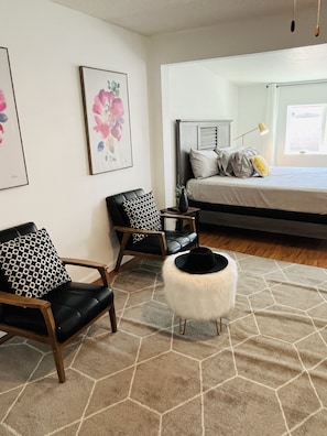 A bedroom with a bed, two chairs, a small stool, and a rug. - Charming Getaway Experience (Chandler)