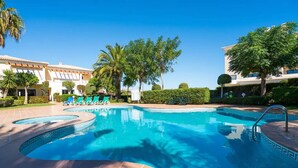 A swimming pool with a curved design, surrounded by lounge chairs and palm trees.