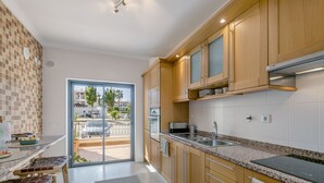 A modern kitchen with wooden cabinets, a granite countertop, and a large window.
