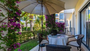 A patio with a round table, wicker chairs, and a laptop.