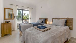A hotel room with two beds, a wooden headboard, a nightstand, a mirror, and a view of the outdoors.