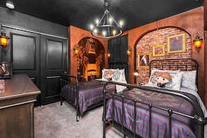 A room with two beds, a desk, and a chandelier.