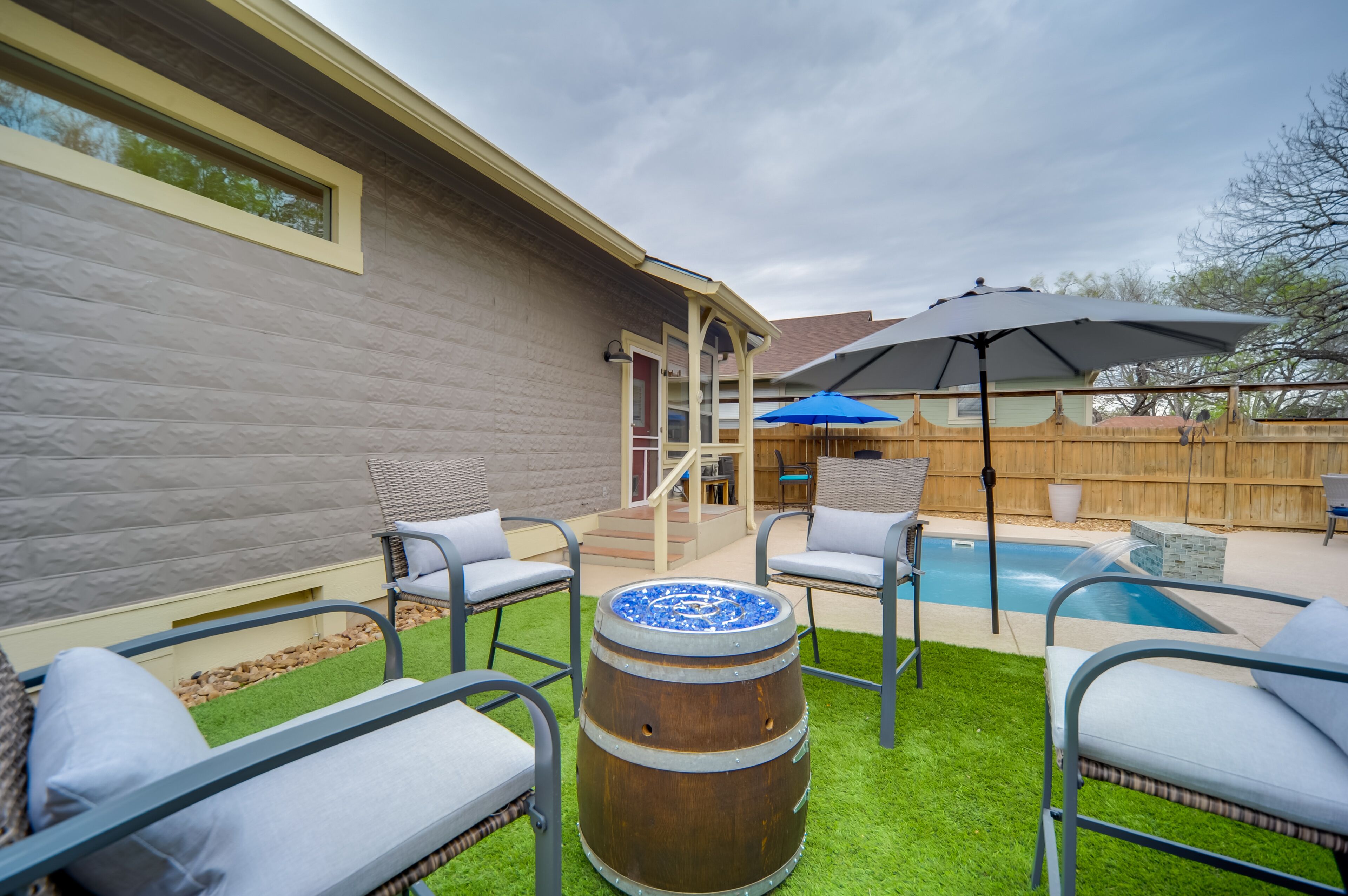Patio con piscina, mobiliario exterior y terraza de madera.