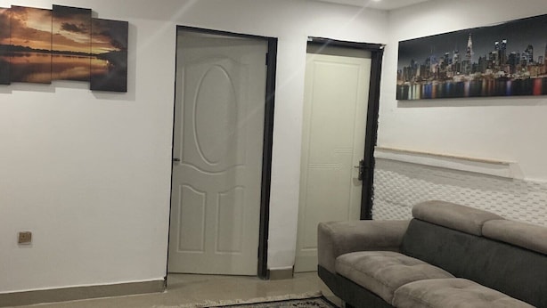 Ein Wohnzimmer mit einer Couch, einem gemusterten Teppich und einem Stadtbild an der Wand.
